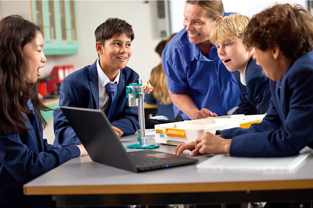 Elever samarbetar med LEGO® Education, dator och en programmerbar modell under en lektion om AI och datavetenskap.