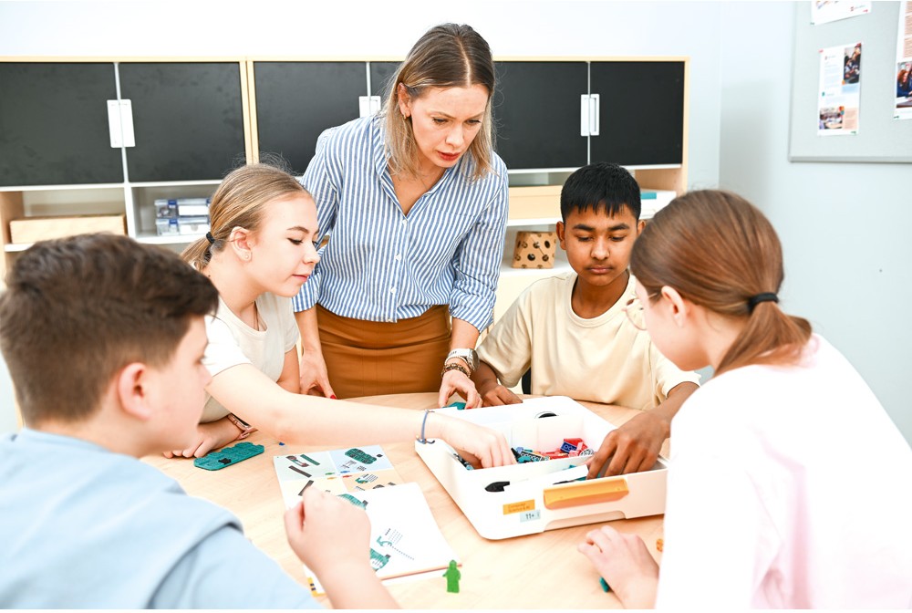 Lärare handleder en grupp elever som samarbetar med LEGO® Education och följer bygginstruktioner.