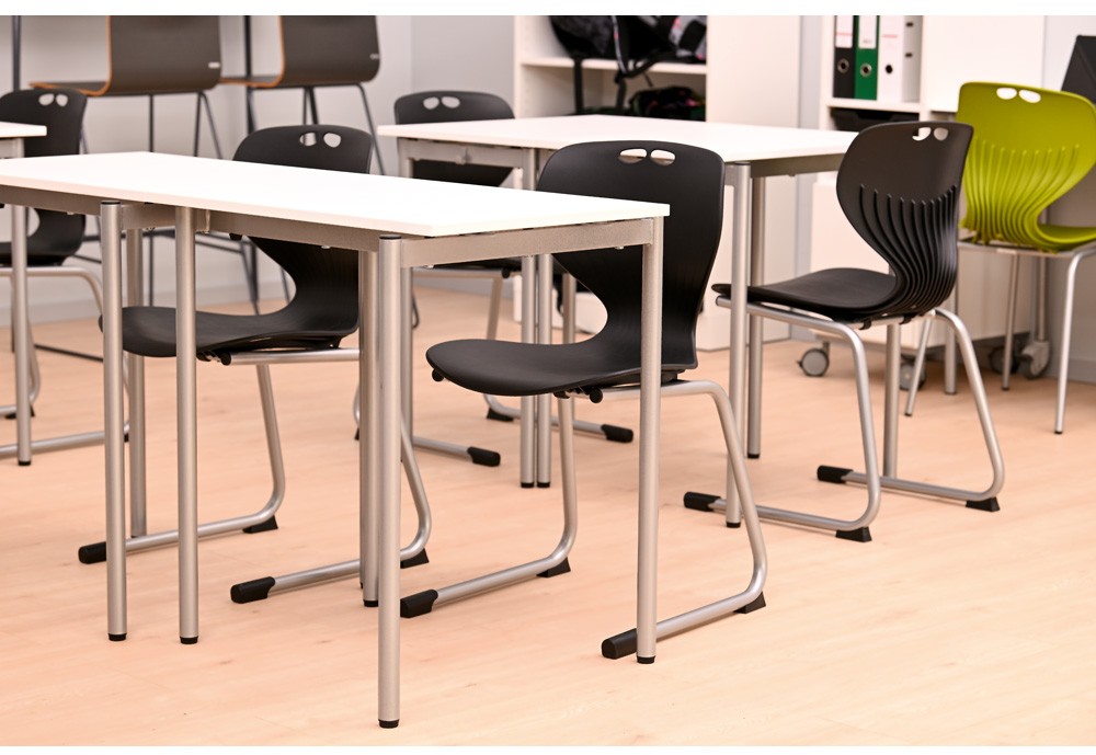 Moderna skolbord och ergonomiska stolar i ett ljust och flexibelt klassrum.