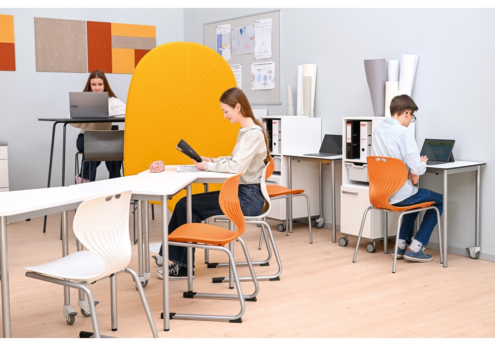 Elever arbetar individuellt i ett modernt klassrum med flexibla arbetsplatser och avskärmning.