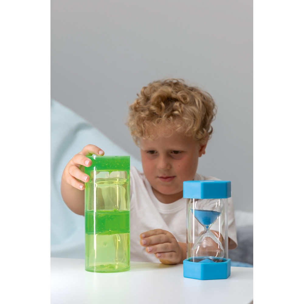 Barn utforskar tid med ett timglas och en sensorisk vätskestimulator under en pedagogisk aktivitet.